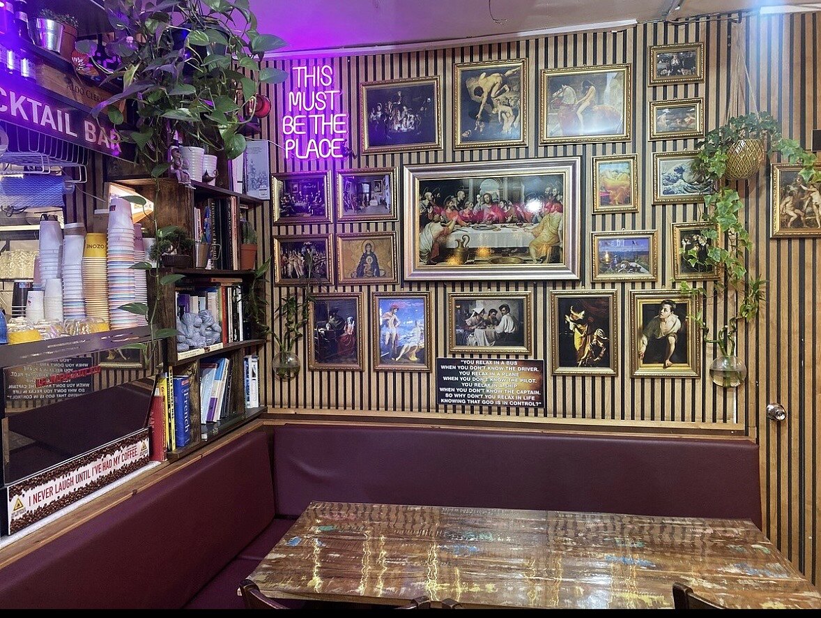 الجزء الداخلي من Artist Cafe London مع جدار فني وطاولات هادئة